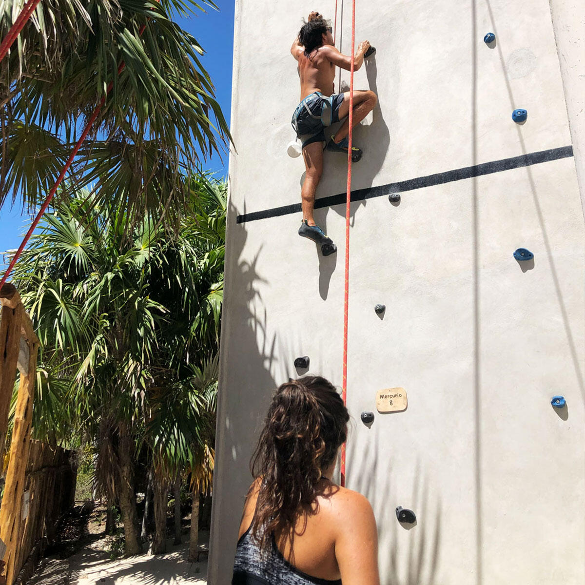 Escalada para todos en Cuyo Climbing Un adulto escala el muro con cuerda mientras una mujer lo asegura desde el suelo.
